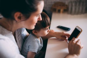 Madre e bambino che guardano insieme uno smartphone - privacy minori sui social